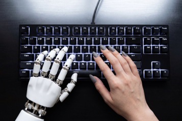 Robotic hand and human hand typing together on backlit keyboard, collaboration between technology and person in modern workspace expressing teamwork and contrast